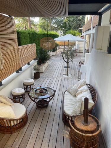 une terrasse en bois avec des chaises, un canapé et des tables dans l'établissement Maison Condorcet, à Saint-Étienne