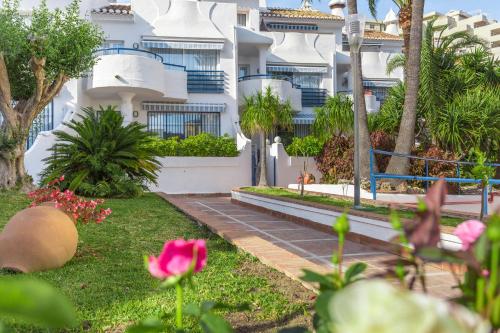 a white apartment building with palm trees and pink flowers at Sahara Sunset in Benalmádena