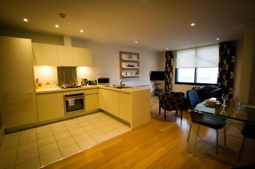 a kitchen and a living room with a table at Merchant Quarters Apartments in Liverpool