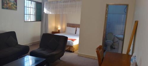 a bedroom with a bed and a chair and a table at Lamerinn Hotel Juba in Juba