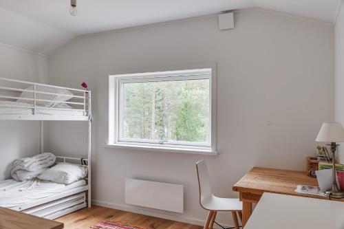 a bedroom with a bunk bed and a desk and a window at Holiday home on Radmanso, Norrtalje with lake view in Norrtälje