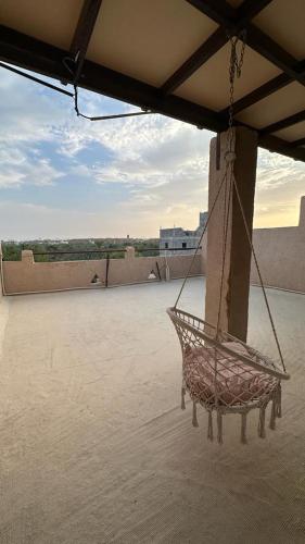 a swinging chair on a patio with a roof at Alqalah Inn in Al Ḩamrāʼ
