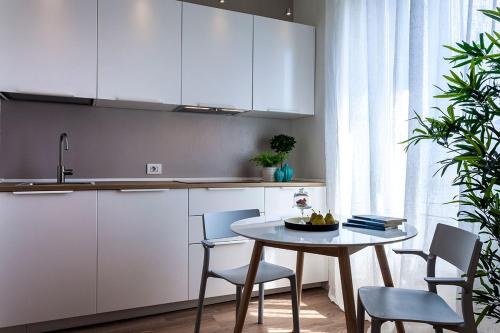 eine Küche mit weißen Schränken sowie einem Tisch und Stühlen in der Unterkunft Pearl House Porta Romana in Mailand