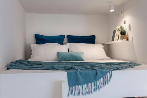 ein Bett mit blauen und weißen Kissen darauf in der Unterkunft Pearl House Porta Romana in Mailand