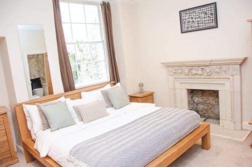 a white bedroom with a large bed and a fireplace at Garden flat in period property Centrally located in Bath