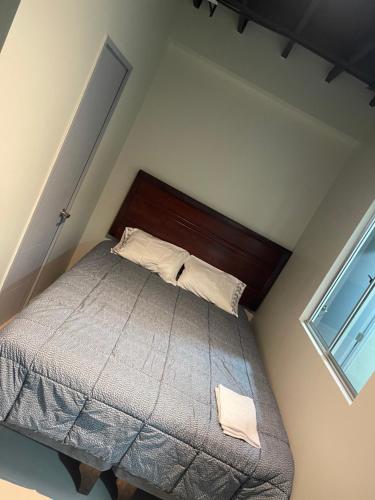 - une chambre avec un lit doté d'une tête de lit en bois et d'une fenêtre dans l'établissement Hostal low cost, à Santiago