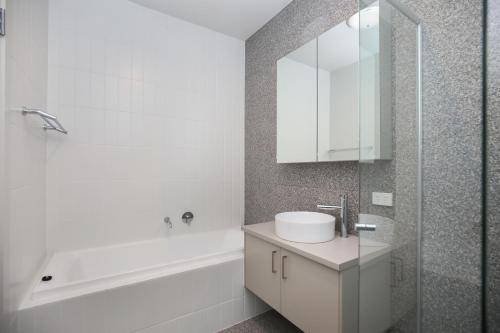 Baño blanco con lavabo, bañera y espejo en Modern house 1double size private bedroom 7min to beach, en Oaklands