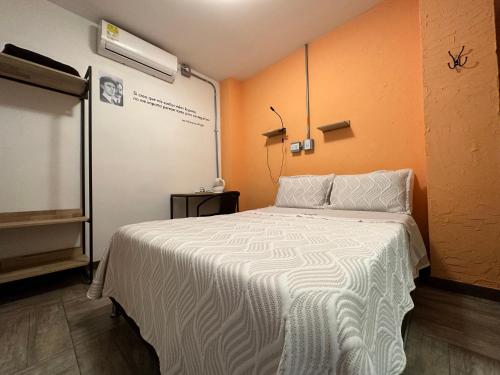 a bedroom with a white bed with an orange wall at CoLinkHouse Hotel in Medellín