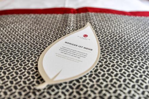 a white tag on top of a bed at Hotel & Restaurant Michaelis in Leipzig