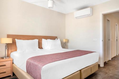 a bedroom with a large white bed with white pillows at Sunset Bay Club in Adeje