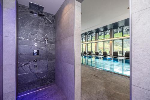 La salle de bains est pourvue d'une piscine et d'une baignoire avec douche. dans l'établissement Thermal-Badhotel Kirchler, à Tux