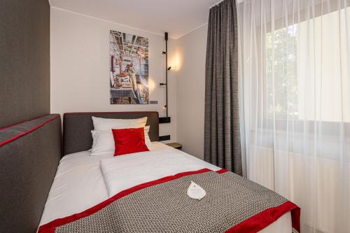a bedroom with a bed with a red pillow and a window at Hotel & Restaurant Michaelis in Leipzig