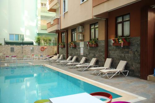 een hotelzwembad met stoelen en een gebouw bij SARAY APART OTEL in Alanya
