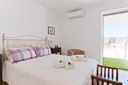 a bedroom with a white bed with towels on it at BmyGuest Collection - Meco Sunset & Pool Villa in Sesimbra