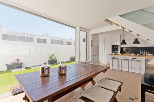 a kitchen with a wooden table and a large window at BmyGuest Collection - Meco Sunset & Pool Villa in Sesimbra