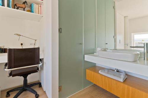 a bathroom with a sink and a desk with a chair at BmyGuest Collection - Meco Sunset & Pool Villa in Sesimbra
