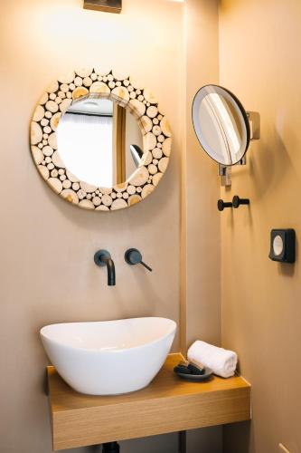 a bathroom with a white sink and a mirror at Mirthea Suites in Mírthios