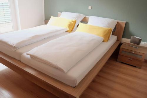 Duas camas com almofadas brancas e amarelas num quarto em Ferienwohnung Merkurblick em Gernsbach