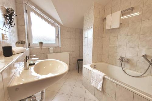 een witte badkamer met een wastafel en een bad bij Ferienwohnung Merkurblick in Gernsbach