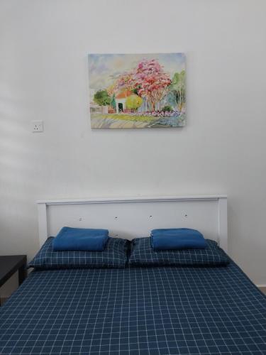 1 cama con almohadas azules y una pintura en la pared en 4 airconditioned rooms and fully furnished Guesthouse in Muar Town en Muar