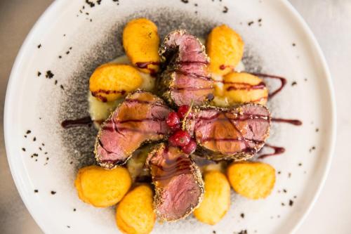 a plate of food with meat and oranges at Hotel Union in Dobbiaco