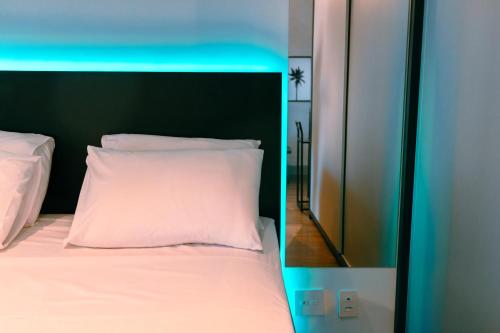 a bed with a white pillow and a mirror at Studio a 100m Bosque, Centro e Cambuí- Home Office, Piscina, Sauna, Jacuzzi, Fitness in Campinas