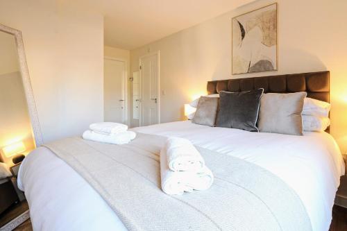 a bedroom with a large white bed with towels on it at Fairfields View in Milton Keynes