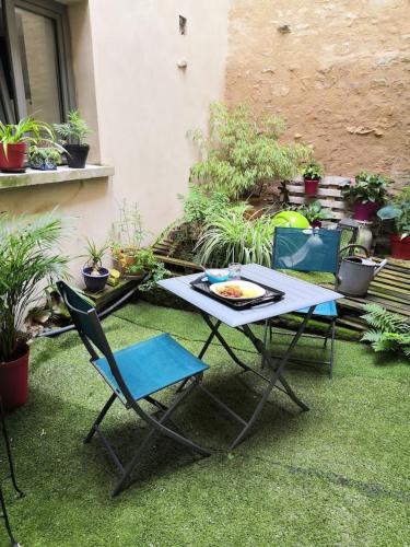 a table and chairs on the grass with plants at Le patio d'antan, le cosy in Florémont