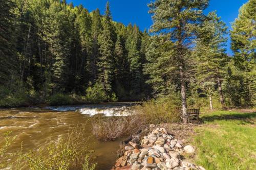 a river with a pile of rocks next to a forest at Slippery Rock River Ranch in Dolores