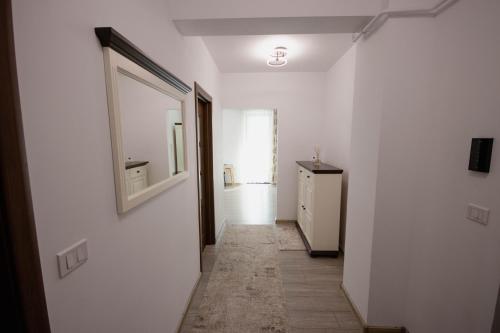 a hallway with a mirror and a white wall at DownTown Apartments in Rădăuţi