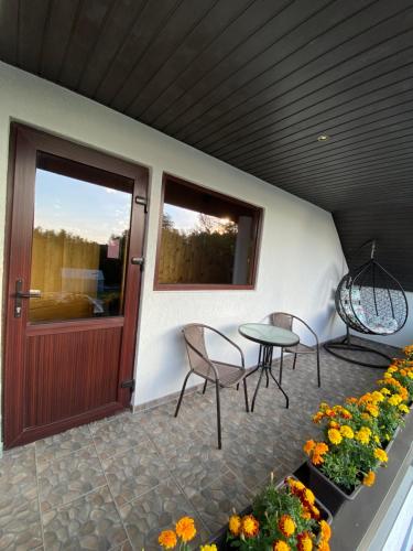 - une terrasse couverte avec une table, des chaises et des fleurs dans l'établissement KRI Holiday House, à Alūksne