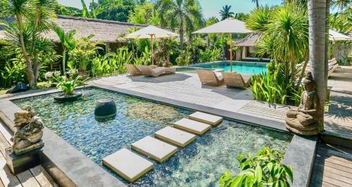 a swimming pool with lounge chairs and a resort at L'Archipel in Gili Islands