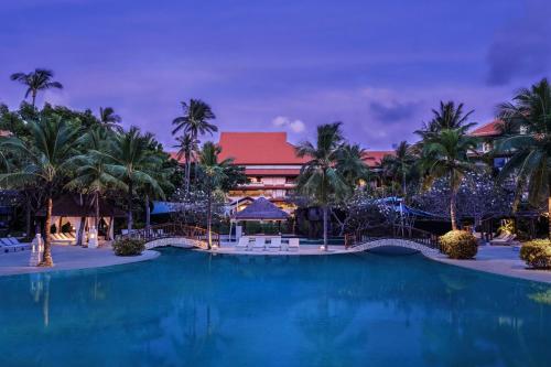 una piscina en un complejo con palmeras y un edificio en The Westin Resort Nusa Dua, Bali, en Nusa Dua