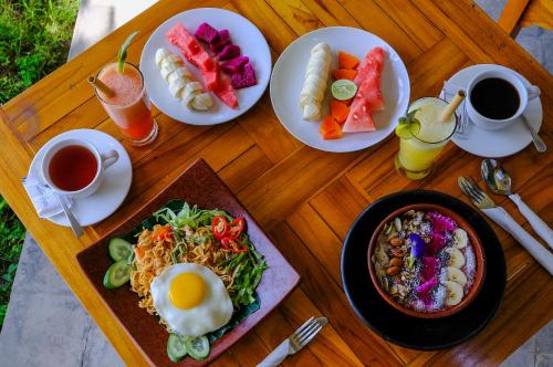 un tavolo in legno con piatti di cibo e tazze di caffè di L'Archipel a Gili Air