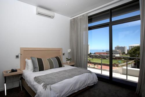 een slaapkamer met een bed en een groot raam bij Head South Lodge in Kaapstad
