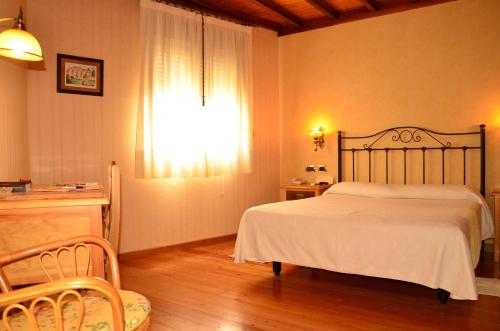 a bedroom with a bed and a desk and a window at TERRA de Lestrove - Quality Rooms in Padrón