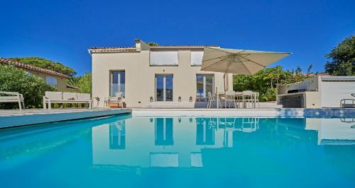 une villa avec une piscine et un parasol dans l'établissement Villa bleu Tropez, à Gassin