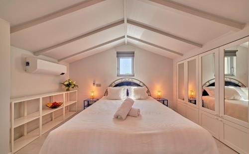 a white bedroom with a large bed with two beds at Villa bleu Tropez in Gassin