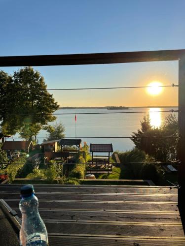 a bottle sitting on a window sill with a view of the water at Apartamenty Fuleda nad jeziorem Dobskim Mazury Holiday in Fuleda