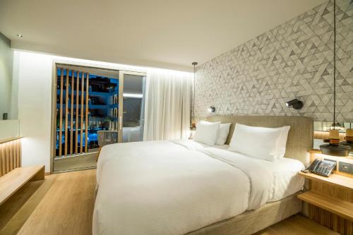 a bedroom with a large white bed and a window at AKASHA Beach Hotel & Spa in Hersonissos