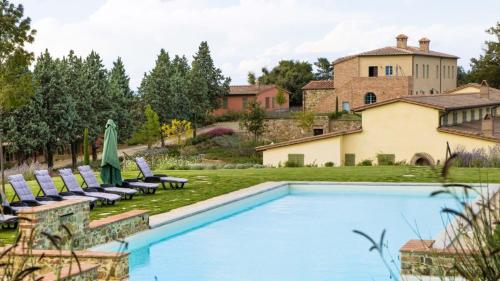 Osteria Delle Noci的住宿－ISA - Luxury Resort with swimming pool immersed in Tuscan nature, Villas on the ground floor with private outdoor area with panoramic view，一个带椅子的游泳池和一个背景房子