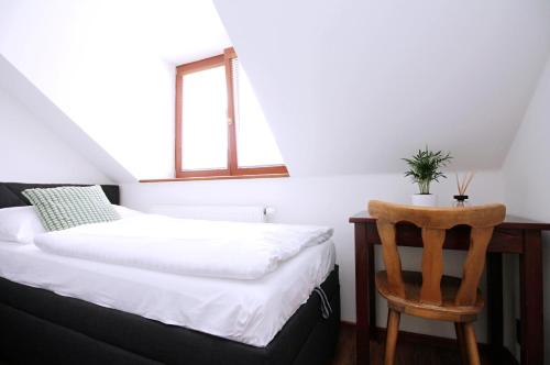 1 dormitorio con cama y silla de madera en Penzion u Zajíčku en Horákov