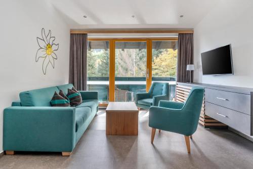 un soggiorno con 2 sedie blu e una TV di Alpine Club Resort a Schladming