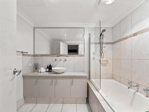 a white bathroom with a tub and a sink at Townhouse 212 in Margaret River Town