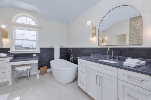 La salle de bains est pourvue d'une baignoire, d'un lavabo et d'un miroir. dans l'établissement 2876 - The Blue Martini by Resort Realty, à Duck