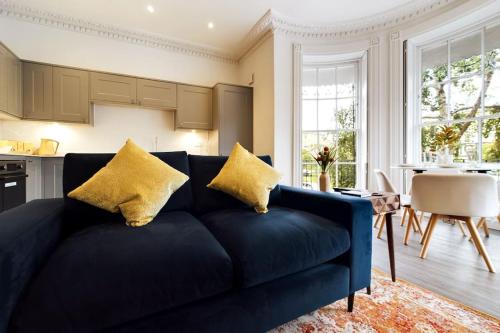 a blue couch with yellow pillows in a living room at Belle Vue Regency King size w Free Parking in Cheltenham