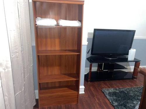 a wooden book shelf with a television and a desk at Nice and quiet appartement in Philadelphia