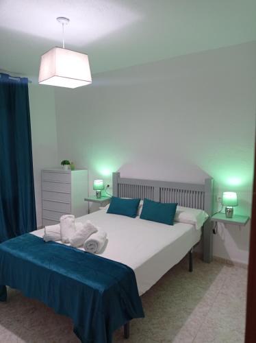 ein Schlafzimmer mit einem großen weißen Bett mit blauen Kissen in der Unterkunft Apartamento La Reina Home in Córdoba