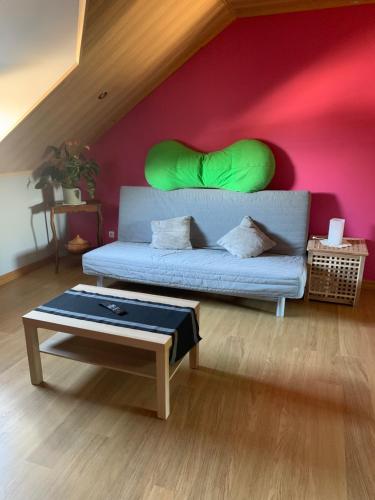 - un salon avec un canapé et un oreiller vert sur le mur dans l'établissement Chambre d'hôtes le Vivaldi, à Seraing
