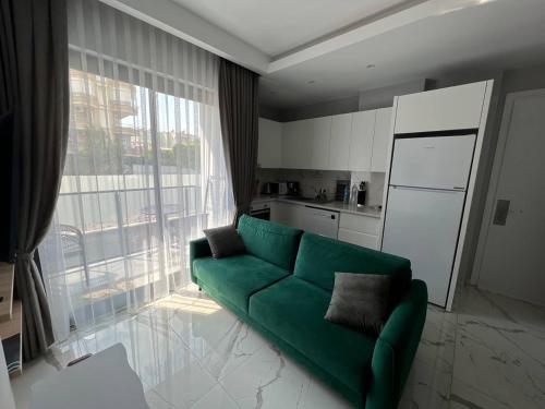 een woonkamer met een groene bank en een keuken bij The Yacht apartments in Alanya